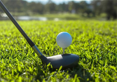 Personalized golf ball resting on a smooth putting green, with golf flag and course landscape in view